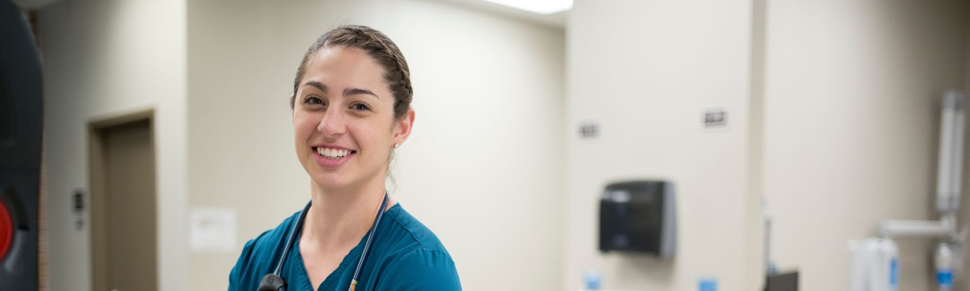 Female nursing student in scrubs smiling.